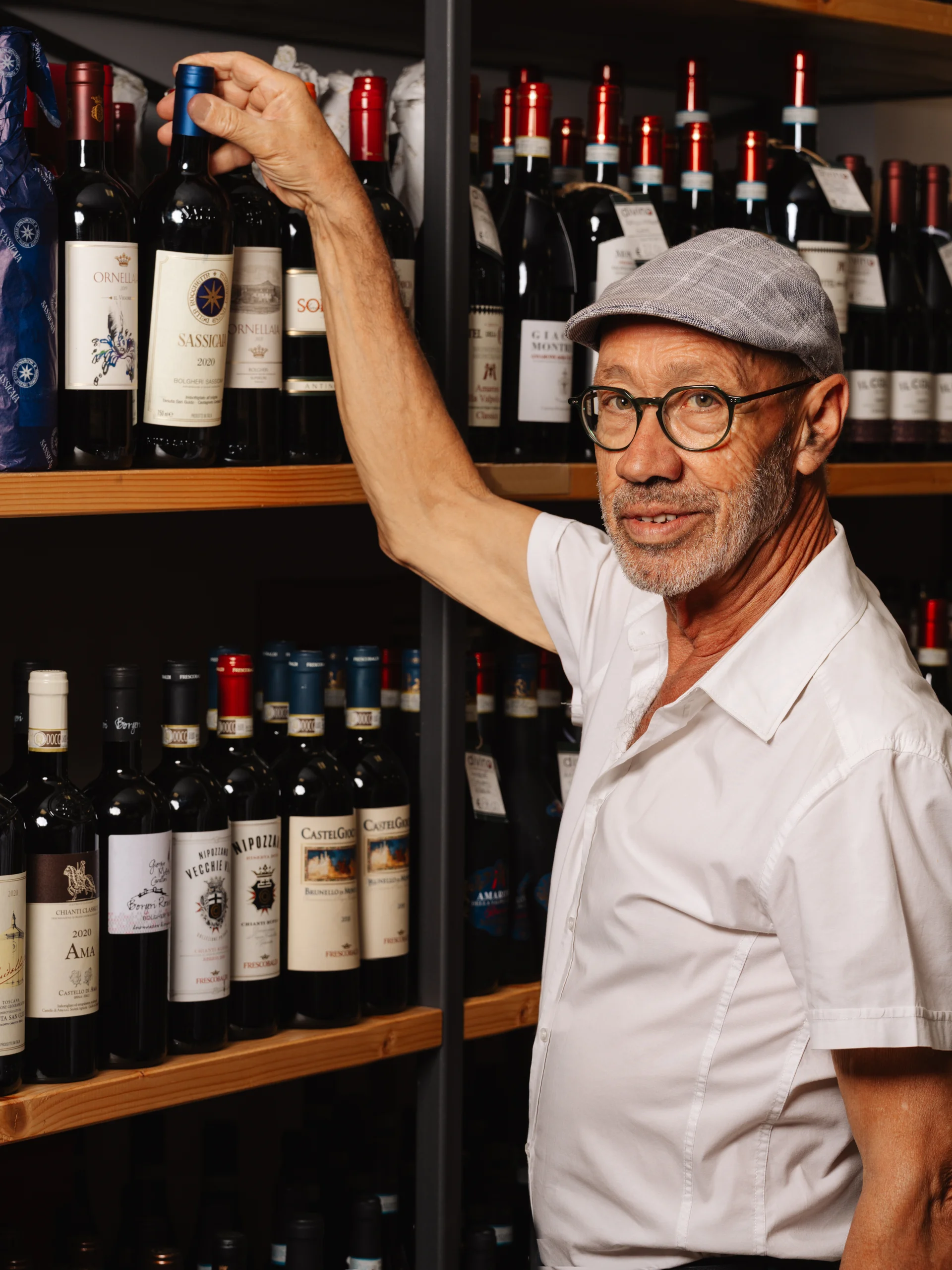 Persona che sceglie una bottiglia di vino in un'enoteca elegante e accogliente